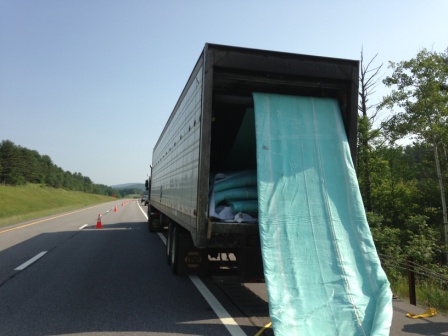 Truck with large blue tarp coming out of the back