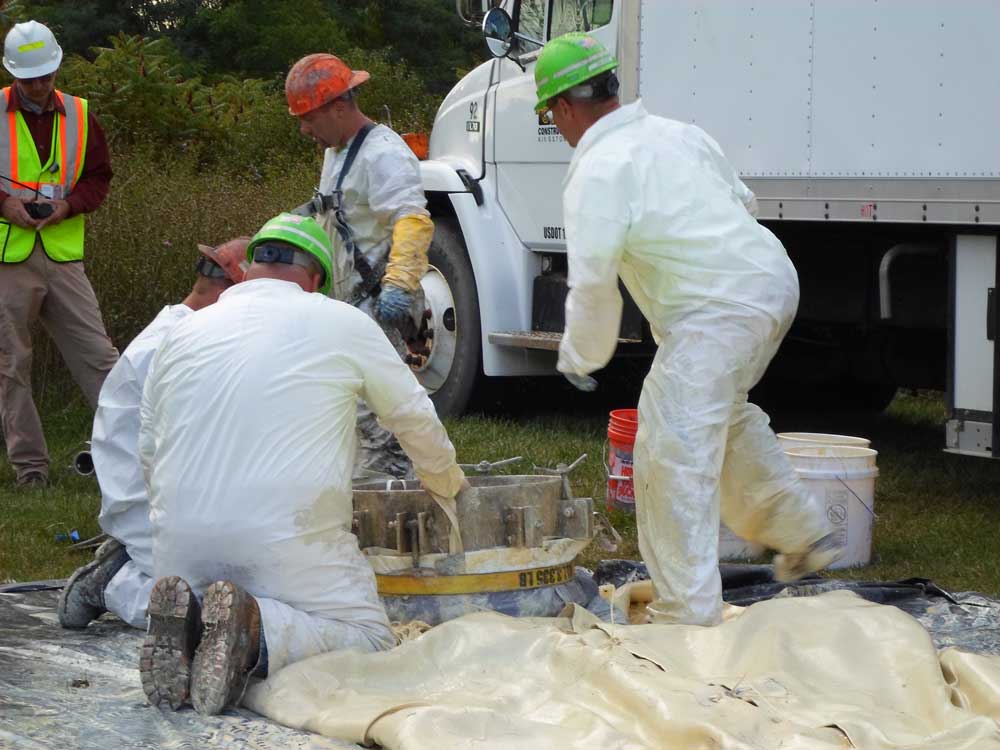 Construction workers in white suits kneeling and working