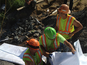 Three construction workers in hole in ground